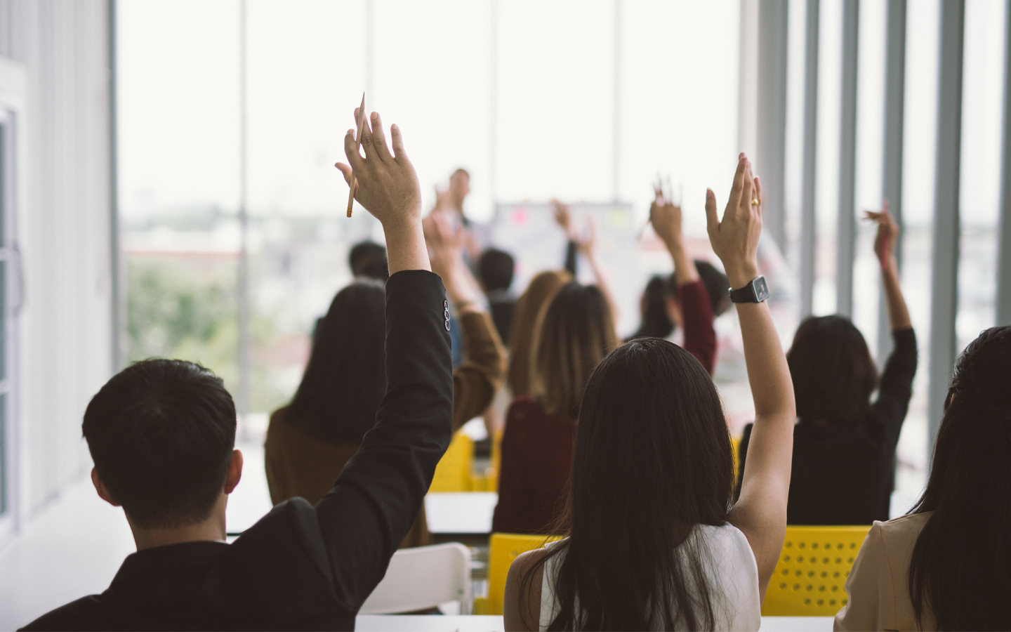 people raising hands in class