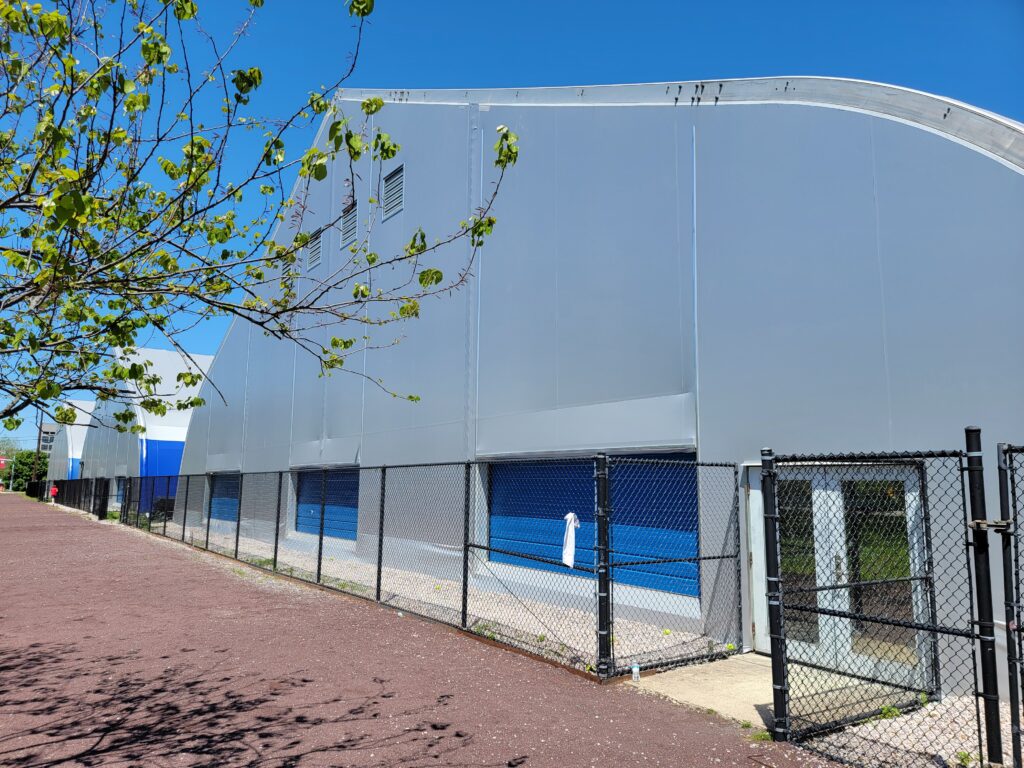 Fabric building with tensioned white panels meeting at aluminum rails along the frame