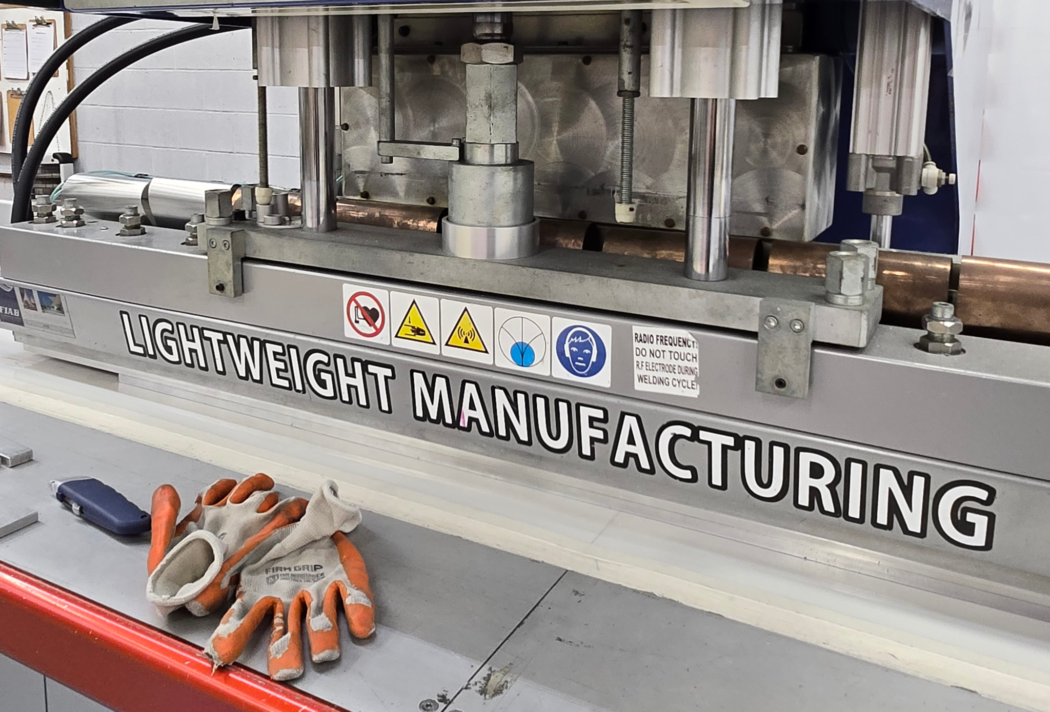 Radio-frequency welding machine on a fabrication bench, with work gloves resting in front of it