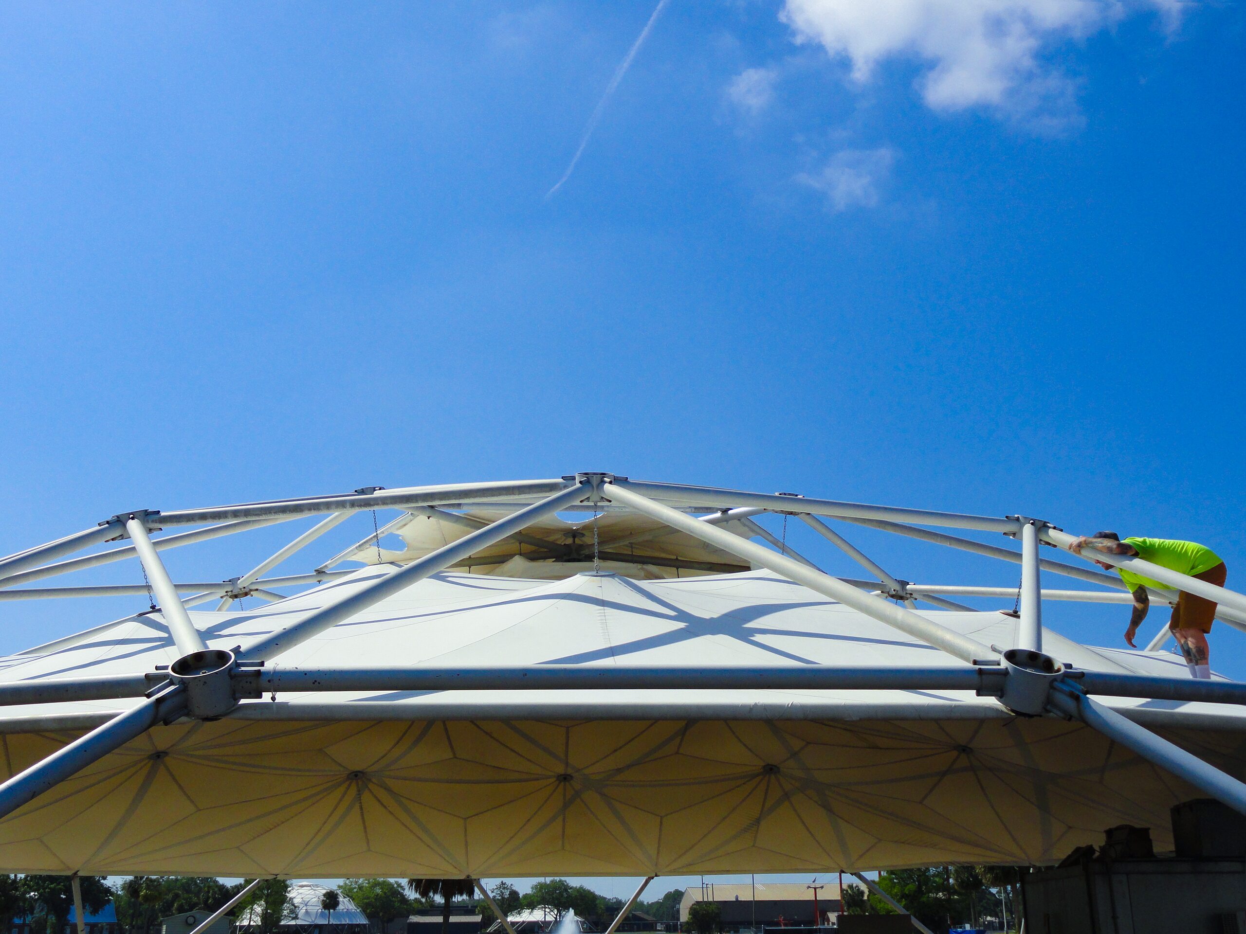 Apex of a tensile canopy seen from below against blue sky