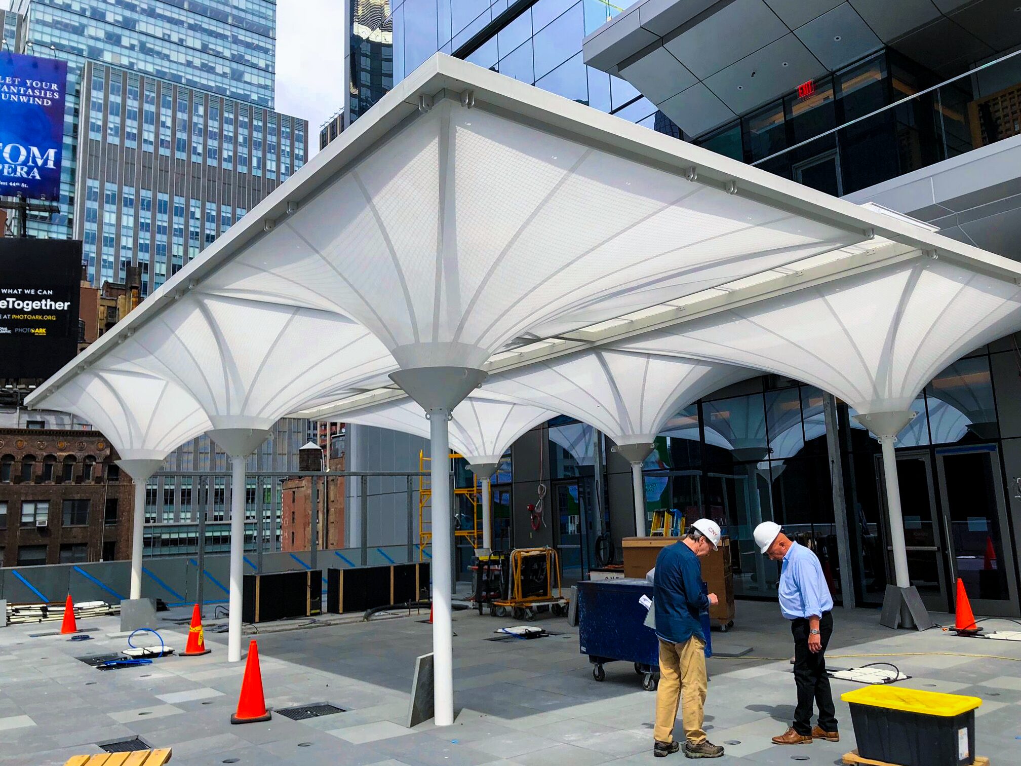 Fabric canopy of inverted cones on white columns over a city plaza